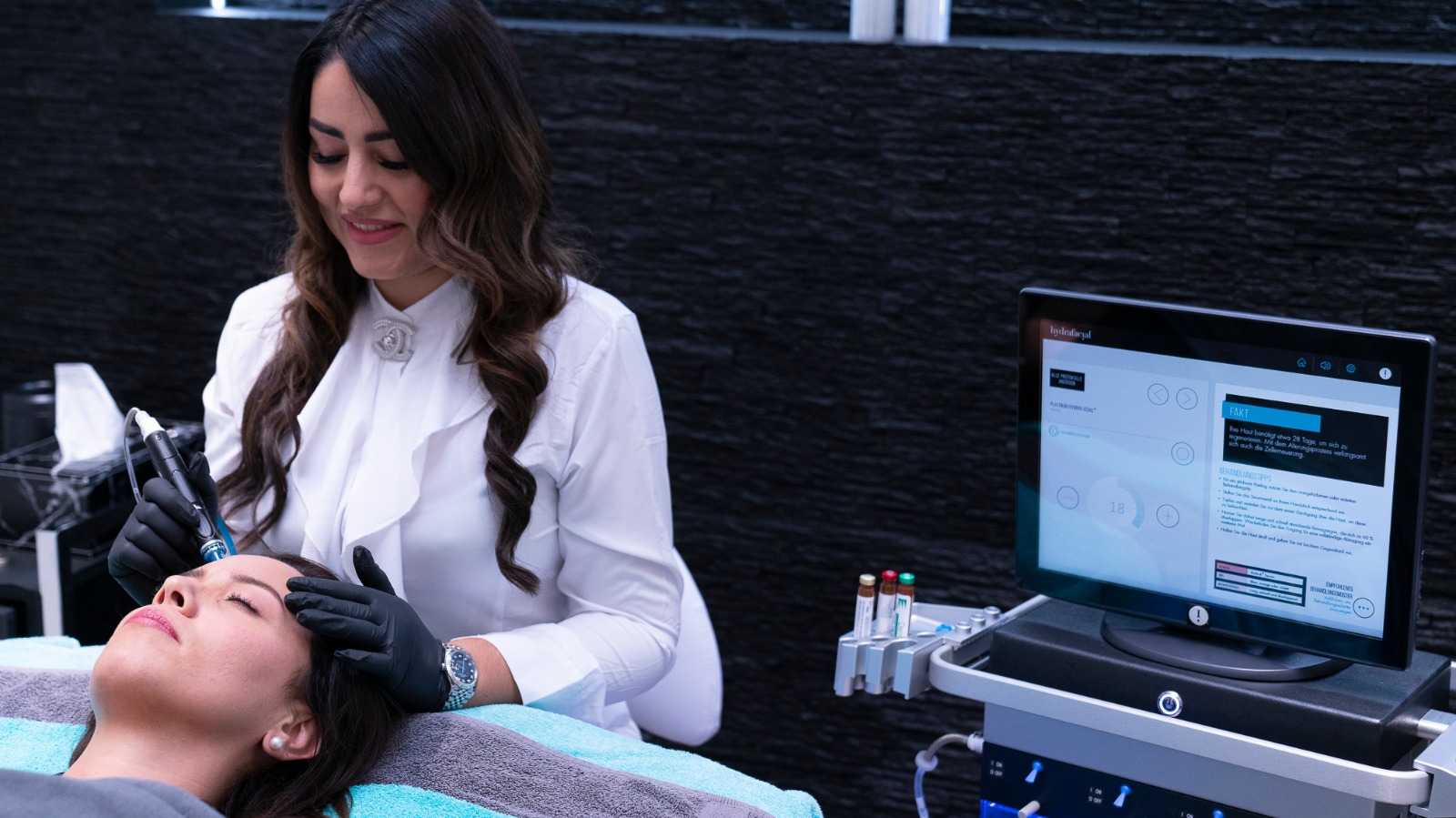 Khatera führt eine HydraFacial-Behandlung an der Stirn einer Kundin durch